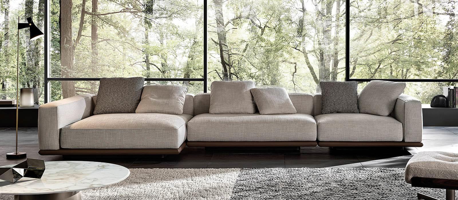 Minotti Horizonte bank met chaise longue, ecru stof, donkerbruine onderrand incl. 2 grijze sierkussens. achtergrond tuin